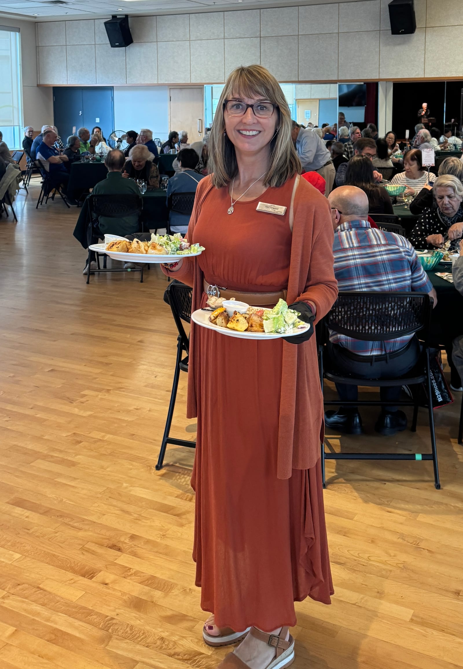 Teri Towner carrying two plates of food while serving guests at the Glen Pine volunteer luncheon.